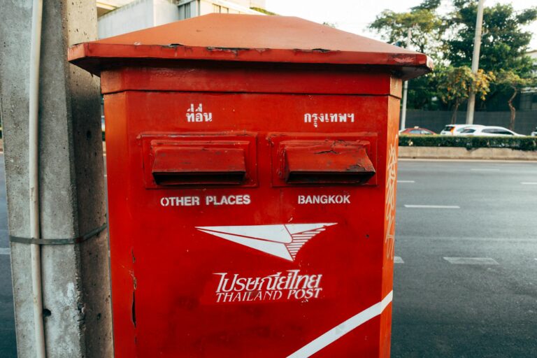 Bright red Thailand post box on a street in Bangkok, capturing urban life.